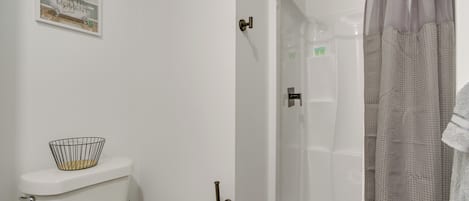 Un baño con ducha, inodoro y una cita enmarcada en la pared.