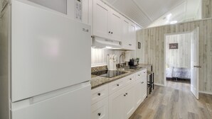 A modern kitchen with white cabinetry, a granite countertop, and a built-in stove. - Picayune Tiny Home Rental ~ 11 Mi to Space Center! (Picayune)