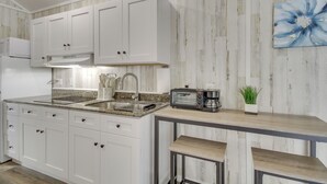 A modern kitchen with white cabinets, a granite countertop, a built-in microwave, a toaster, and a coffee maker. - Cozy Picayune Rental Home ~ 11 Mi to Space Center! (Picayune)