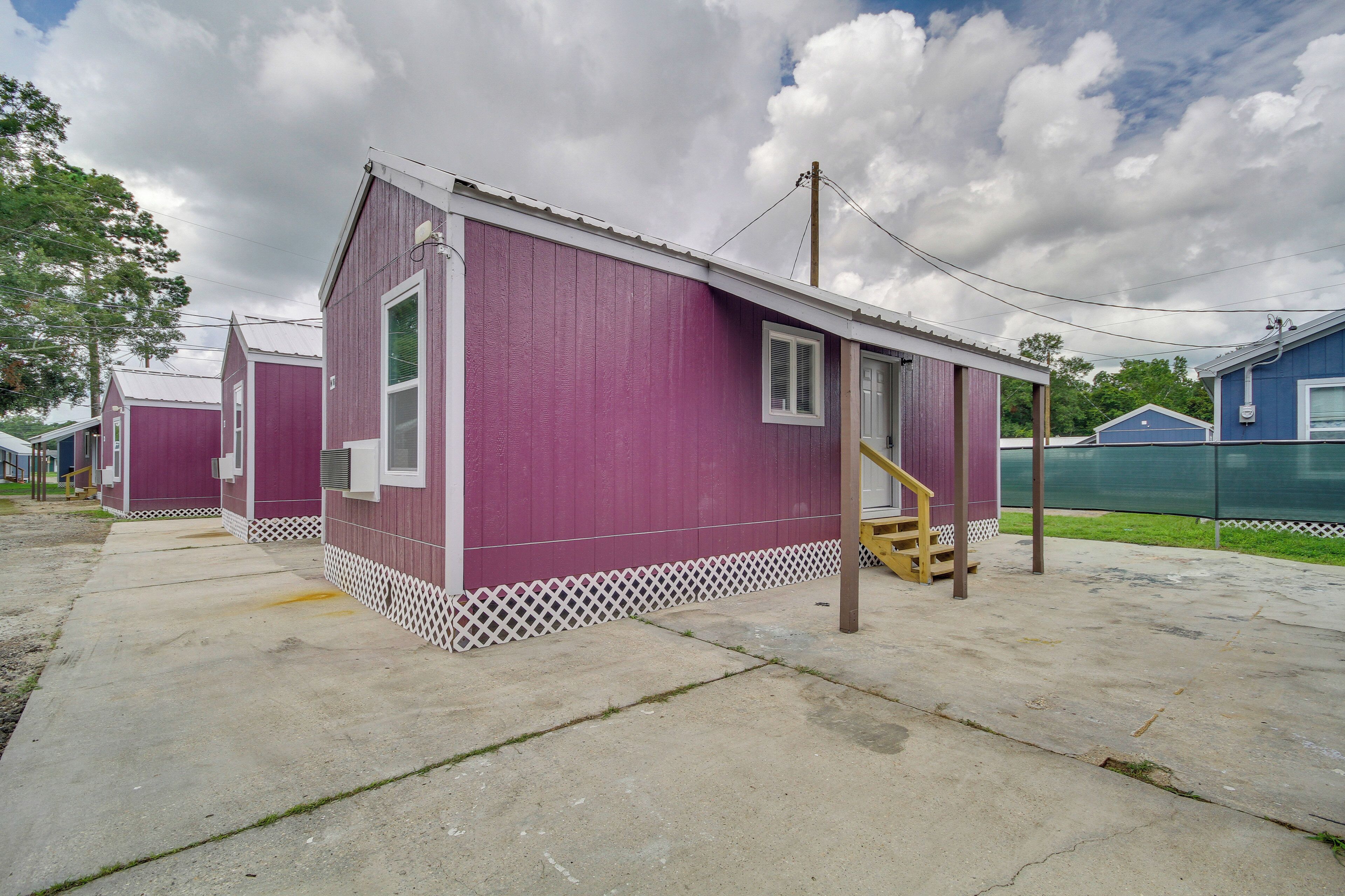 A row of small, single-story cabins with a simple design, featuring a porch and a small staircase leading to the entrance.
