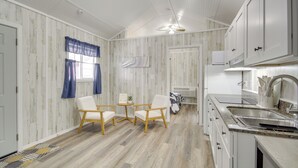 A compact kitchen with white cabinetry, a built-in stove, and a small dining area with two chairs. - Cozy Picayune Rental Home ~ 11 Mi to Space Center! (Picayune)