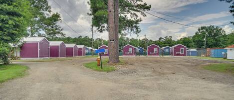 A gravel driveway leading to a row of small, single-story buildings with a mix of purple and blue exteriors.