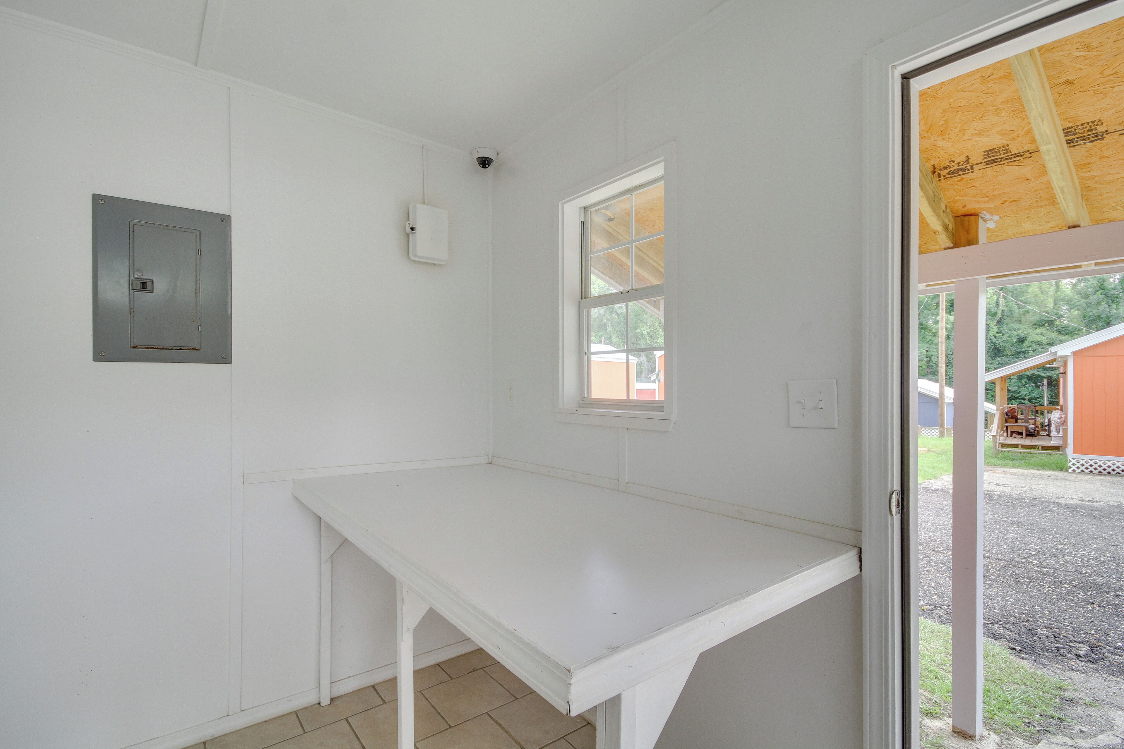 A room with a white table, a window, and a door leading outside.