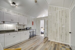 Una cocina moderna con armarios blancos, un microondas y un taburete de bar.