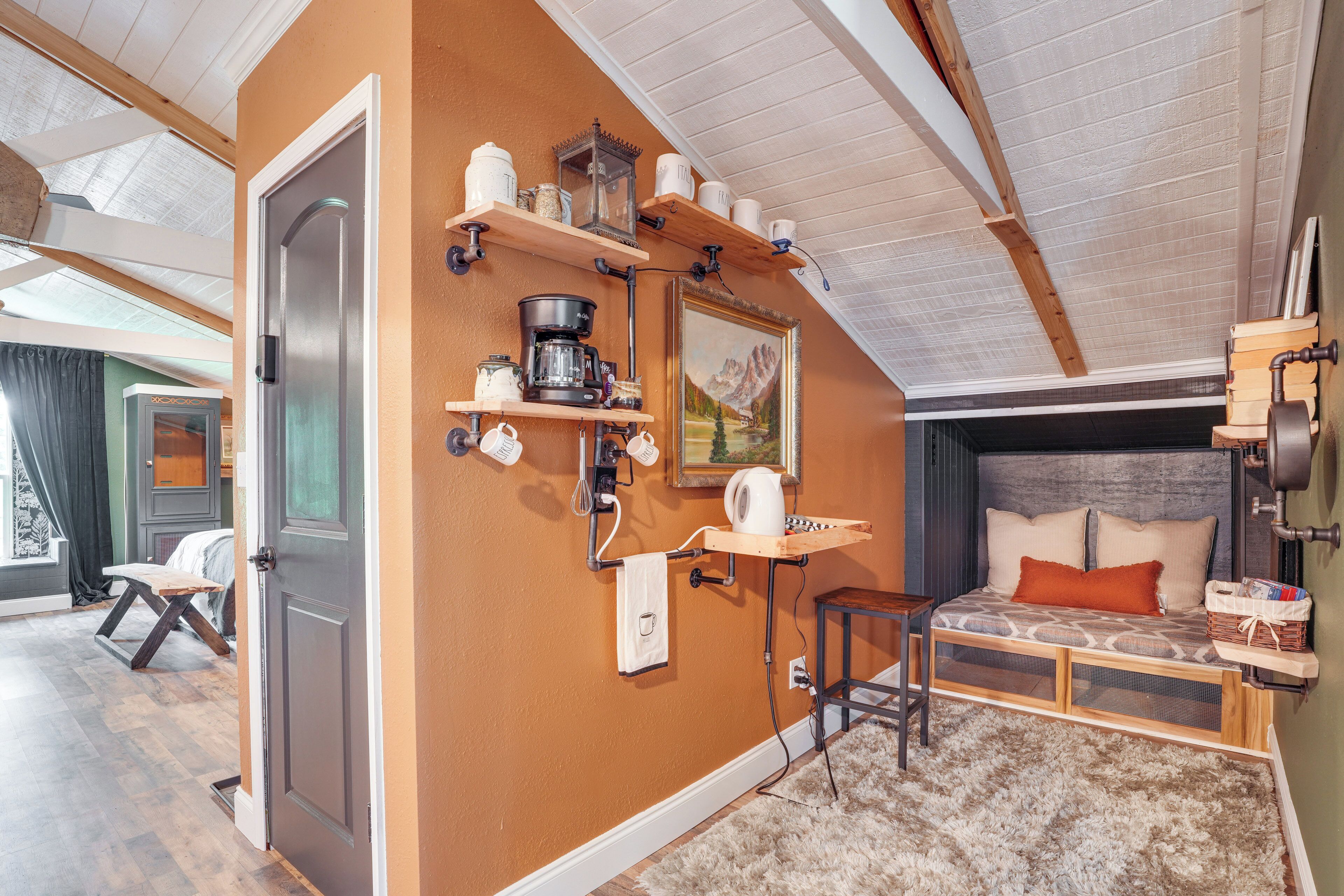 Una habitación acogedora con una cama, un escritorio y estantes con utensilios de cocina.