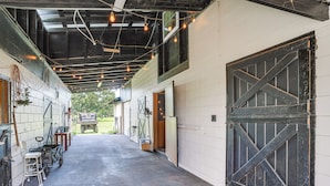 Un garage fermé avec un sol en béton, de grandes portes en bois et un éclairage au plafond.