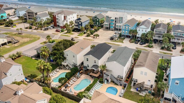 Zona residencial costera con casas, una playa y un complejo de piscinas.