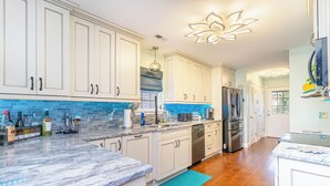 Una cocina moderna con armarios blancos, salpicadero azul y un refrigerador de acero inoxidable.