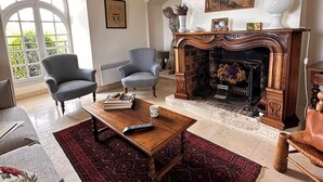 A spacious living room with a fireplace, a chandelier, and a large arched window. - From the top of its terraces and garden, breathtaking views of the Luberon  (Murs)