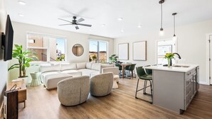 A modern living room with a sofa, two armchairs, a dining area, and a kitchen island. - Lagoon Desert Retreat (St. George)