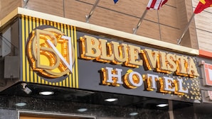 Das Hotel Blue Vista mit beleuchteter Beschilderung und Flaggen.