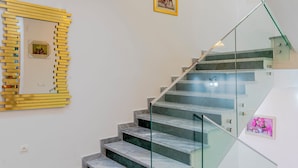 Eine Treppe mit Glastrennstäben und einem goldgerahmten Spiegel an der Wand.