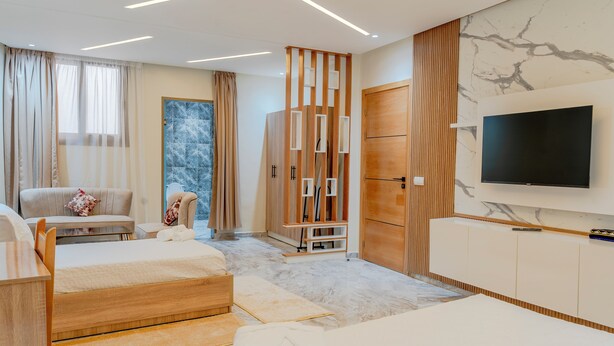 Ein modernes Hotelzimmer mit einem großen Bett, einer Couch, einem Fernseher und einem Kleiderschrank.