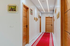 Ein Korridor mit Holztüren, einem roten Teppich und Wanddekorationen.
