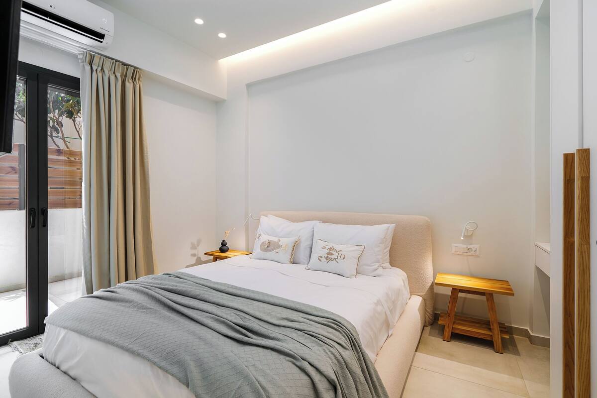 A modern bedroom with a bed, bedside tables, and a view through a glass door.