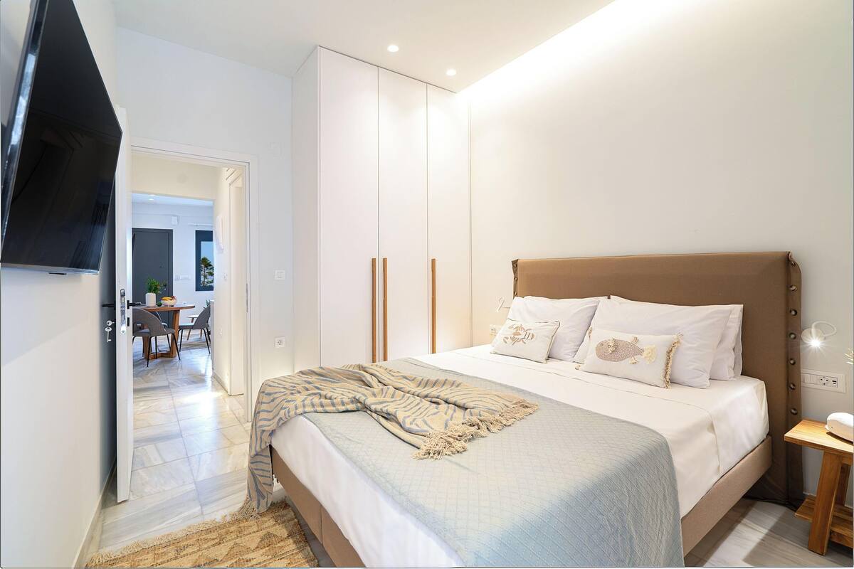 A bedroom with a bed, bedside table, and a TV mounted on the wall.