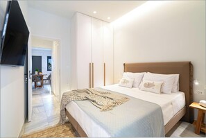 Un dormitorio con cama, mesita de noche y televisor montado en la pared.