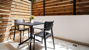 A patio with a table and chairs, a potted plant, and a wooden fence. - Inia Apartments (Malevizi)