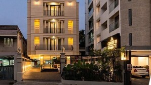 Un hôtel à plusieurs étages au design moderne, doté de balcons et d’une entrée bien éclairée.