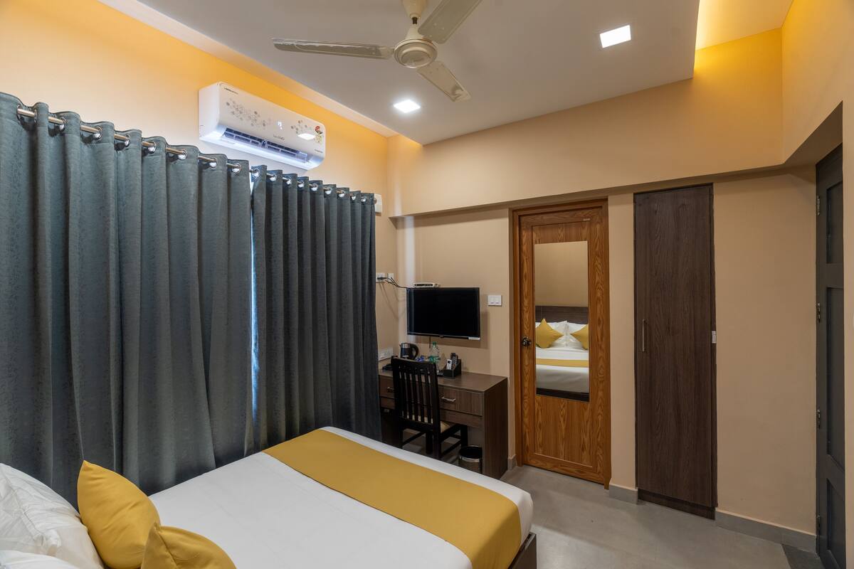 A hotel room with a bed, desk, and television.