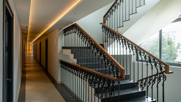 Un escalier moderne avec une main courante en bois et des balustrades en métal, menant à l’étage supérieur.