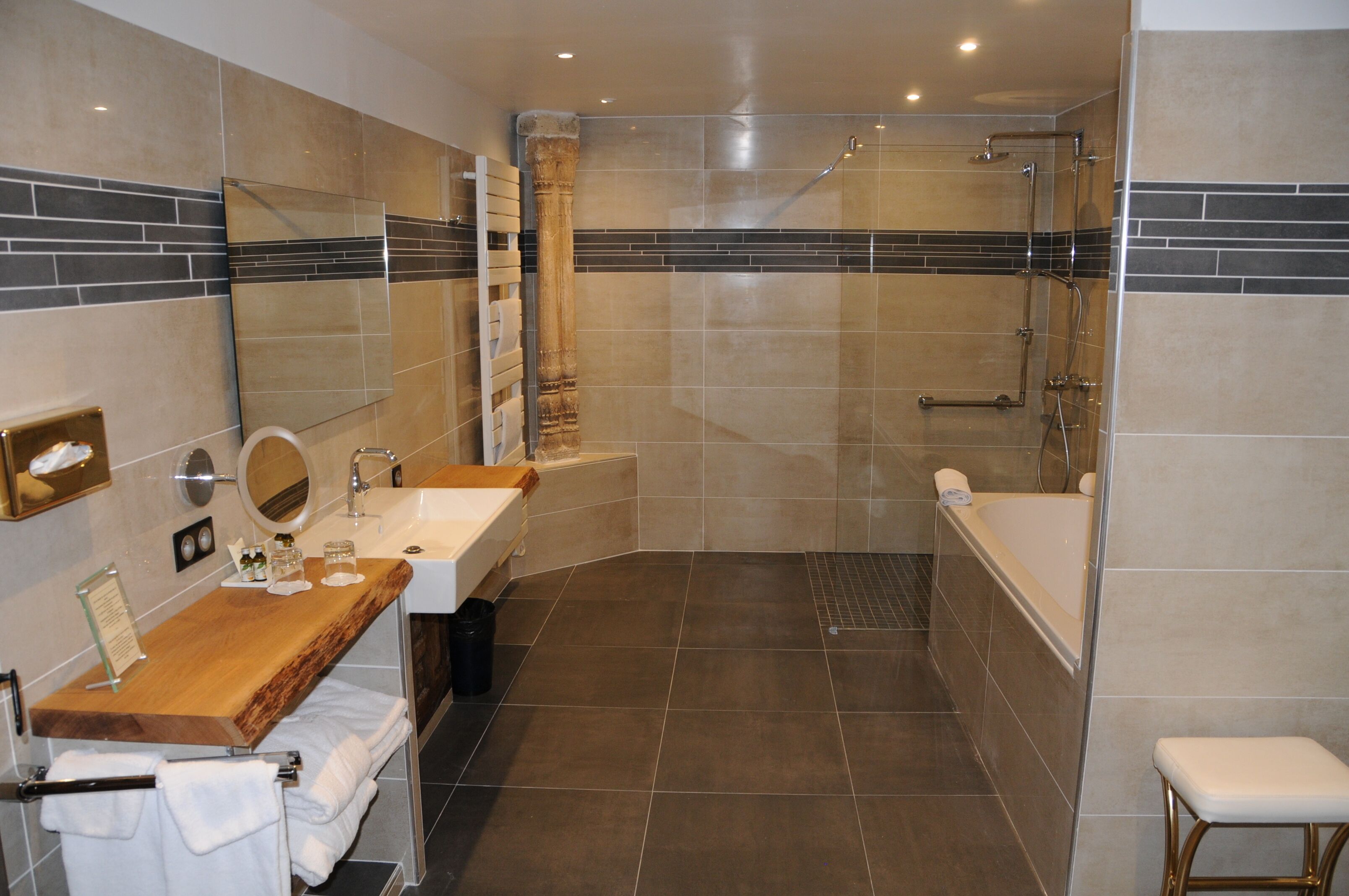 A modern bathroom with a wooden vanity, a large mirror, a bathtub, and a shower area.