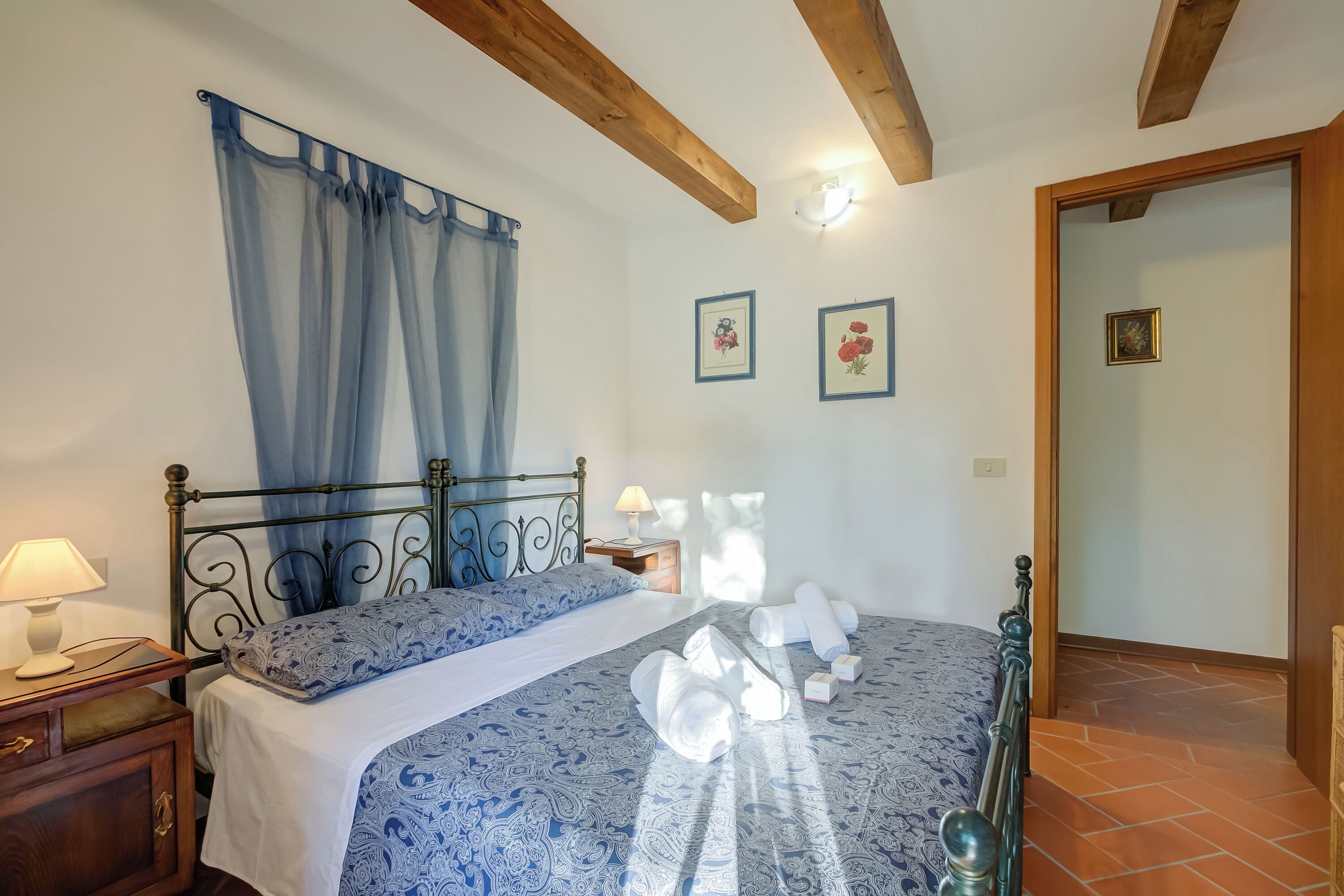 A bedroom with a bed, nightstand, and a wooden ceiling.