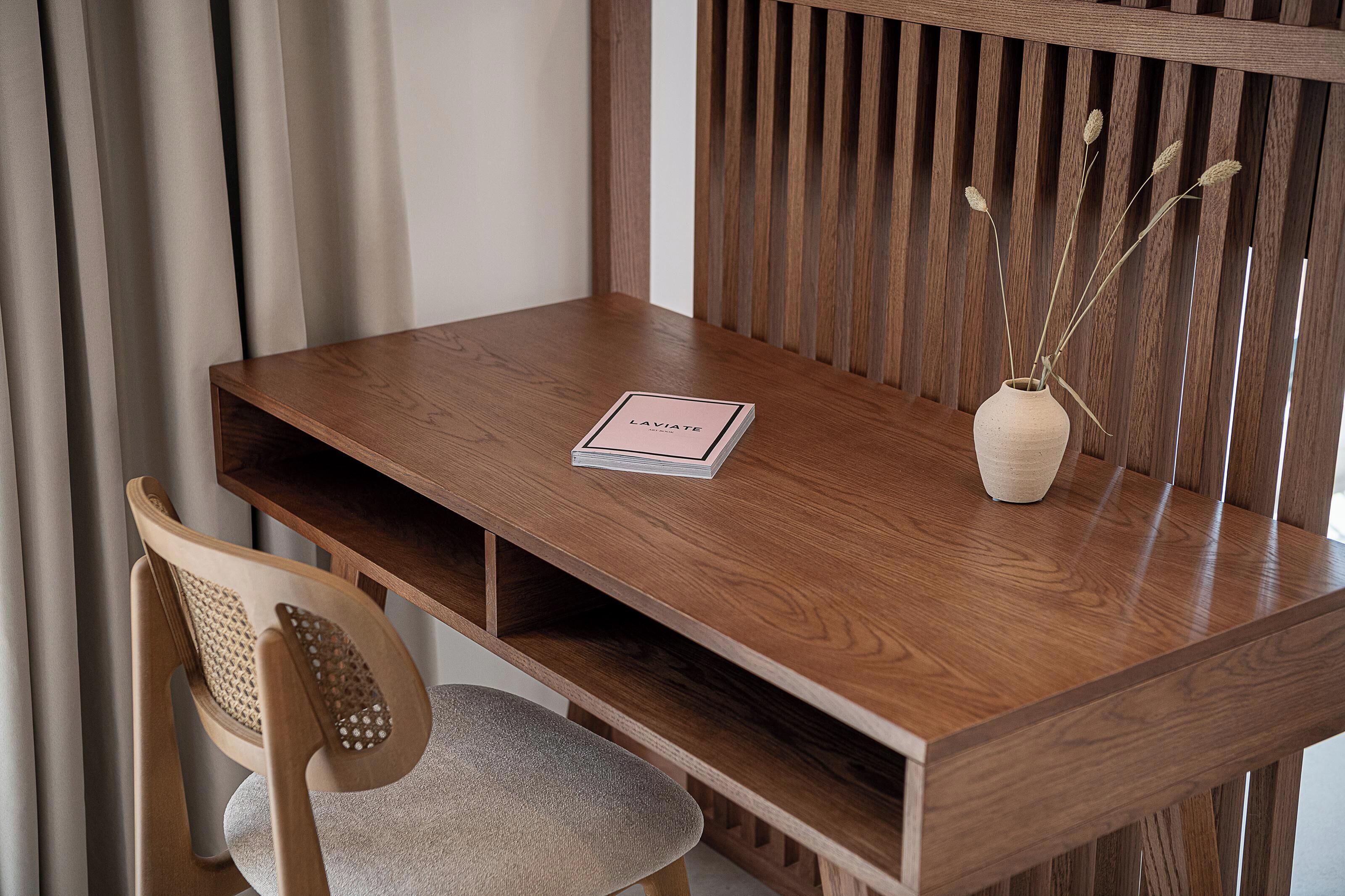 Ein Holztisch mit einem Buch mit dem Titel 'LAVIATE' und einer Vase mit getrockneten Pflanzen.