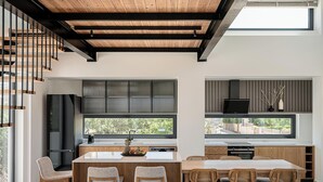 Una cuina moderna amb una illa central, electrodomèstics integrats i grans finestres que donen a l'exterior.