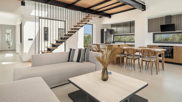 Un interior modern amb una escala, una zona de menjador i una cuina.