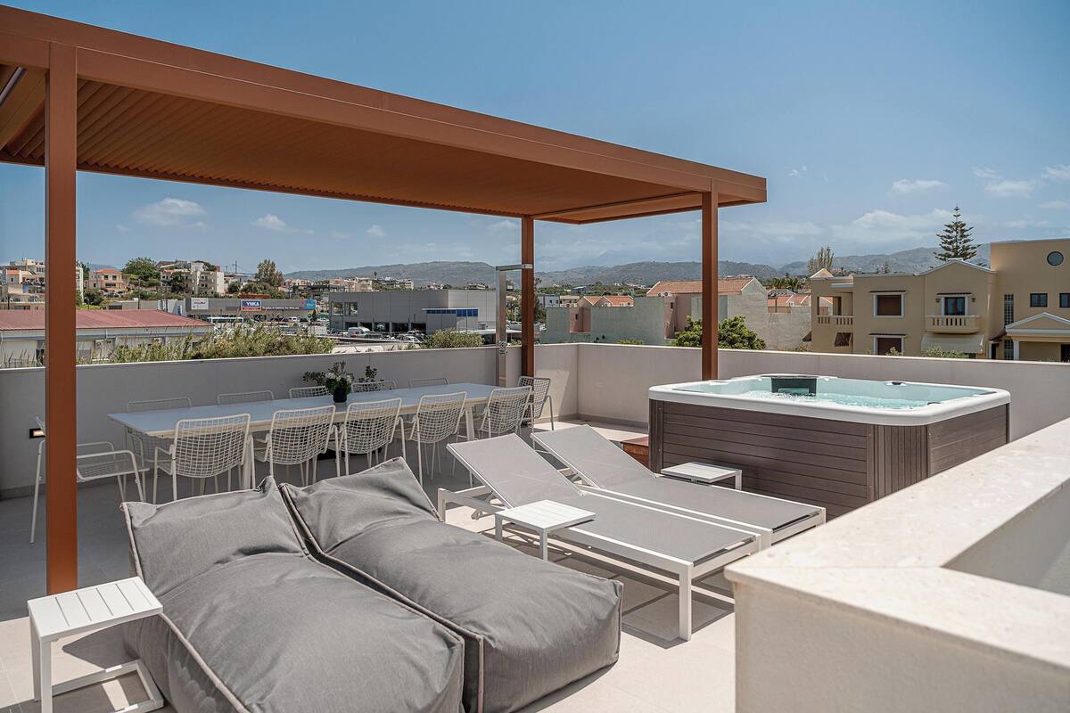 Terraço no telhado com hidromassagem, cadeiras de descanso e uma mesa de jantar.