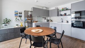 Une cuisine moderne avec des meubles gris, une table ronde en bois et des chaises noires.