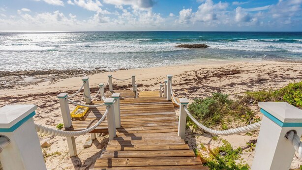 A wooden boardwalk leading to a beach with a clear view of the ocean and a rocky outcrop in the distance. - Cheers - Your Perfect Beachfront Escape with Private Dock Slip Pool Ocean (Hope Town)