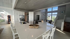 A spacious kitchen with a large island, white cabinetry, and a view of the outdoors. - Cheers - Your Perfect Beachfront Escape with Private Dock Slip Pool Ocean (Hope Town)