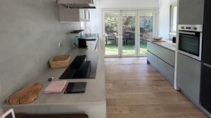 Una cocina moderna con una isla grande, horno empotrado y puertas correderas de vidrio que dan a un patio.