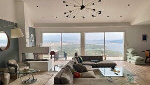 Un salón amplio con un sofá grande, una mesa de centro de vidrio y una lámpara moderna.