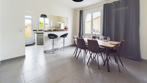Ein moderner Essbereich mit Holztisch, schwarzen Stühlen und Blick in die Küche.