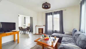 Ein Wohnzimmer mit einer Couch, einem Couchtisch, einem Fernseher, einem Kamin und einem Essbereich mit Stühlen und einem Tisch.