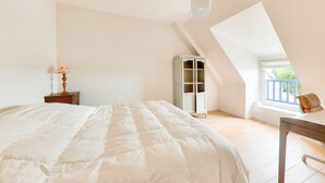 A bedroom with a large bed, a nightstand, a wardrobe, and a window with a view. - Seaview, house for 7 Golfe du Morbihan (Sarzeau)
