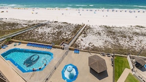 Blick auf einen Strand mit Schwimmbad, Strandstühlen und einem Rettungsturm.