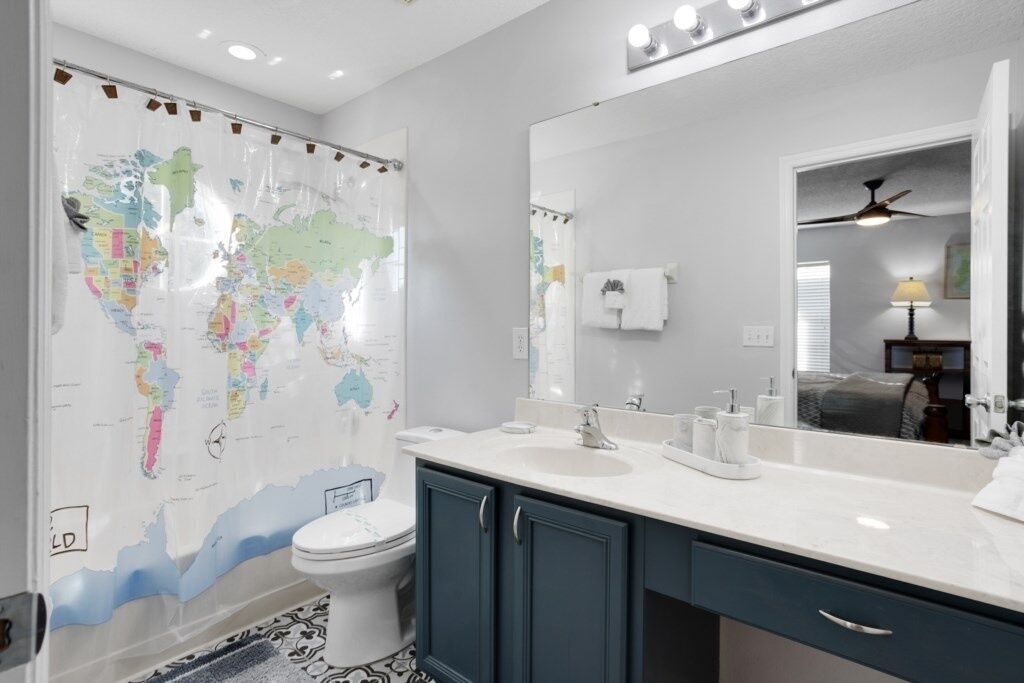 A bathroom with a large mirror, a sink, and a toilet.