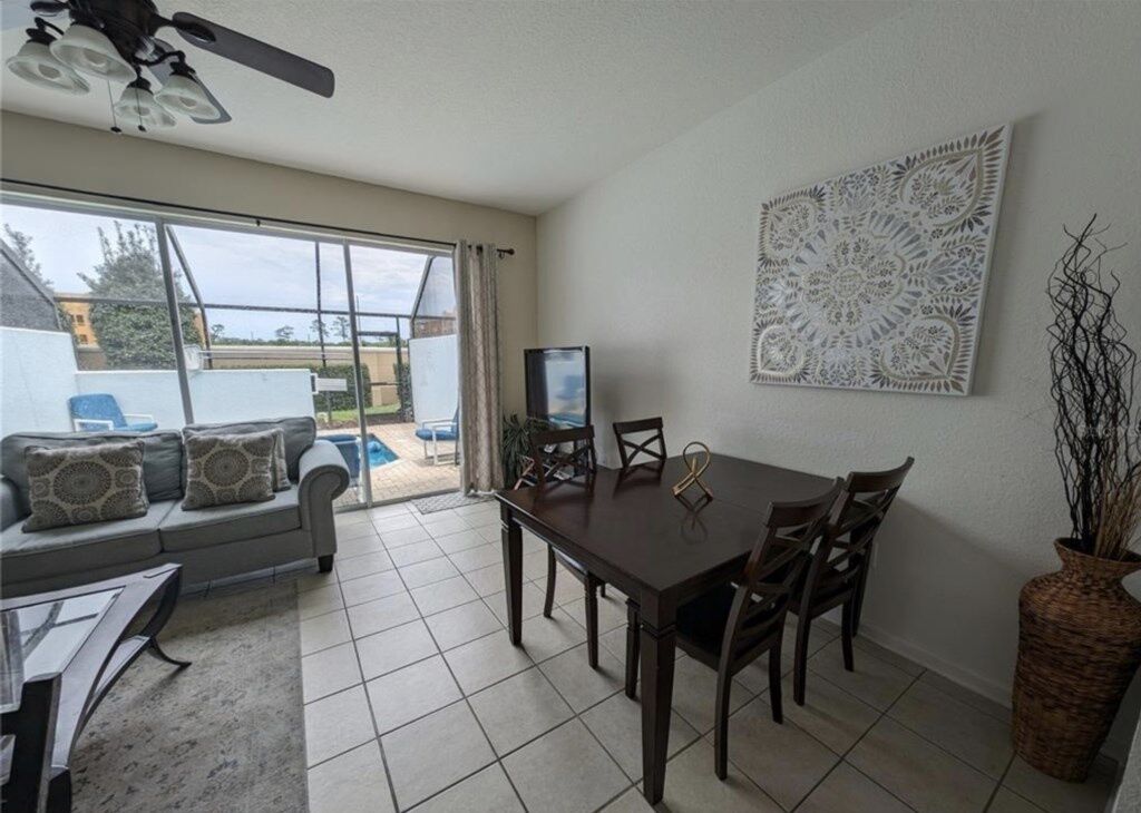 A dining area with a table and chairs, a ceiling fan, and a decorative wall piece.
