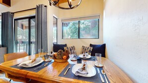 A dining area with a wooden table set for four, featuring plates, cutlery, and glasses. - Bigwood #45 2 Bedroom Condo by RedAwning (Mammoth Lakes)