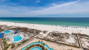 A beach resort with a swimming pool area, beach umbrellas, and a boardwalk.