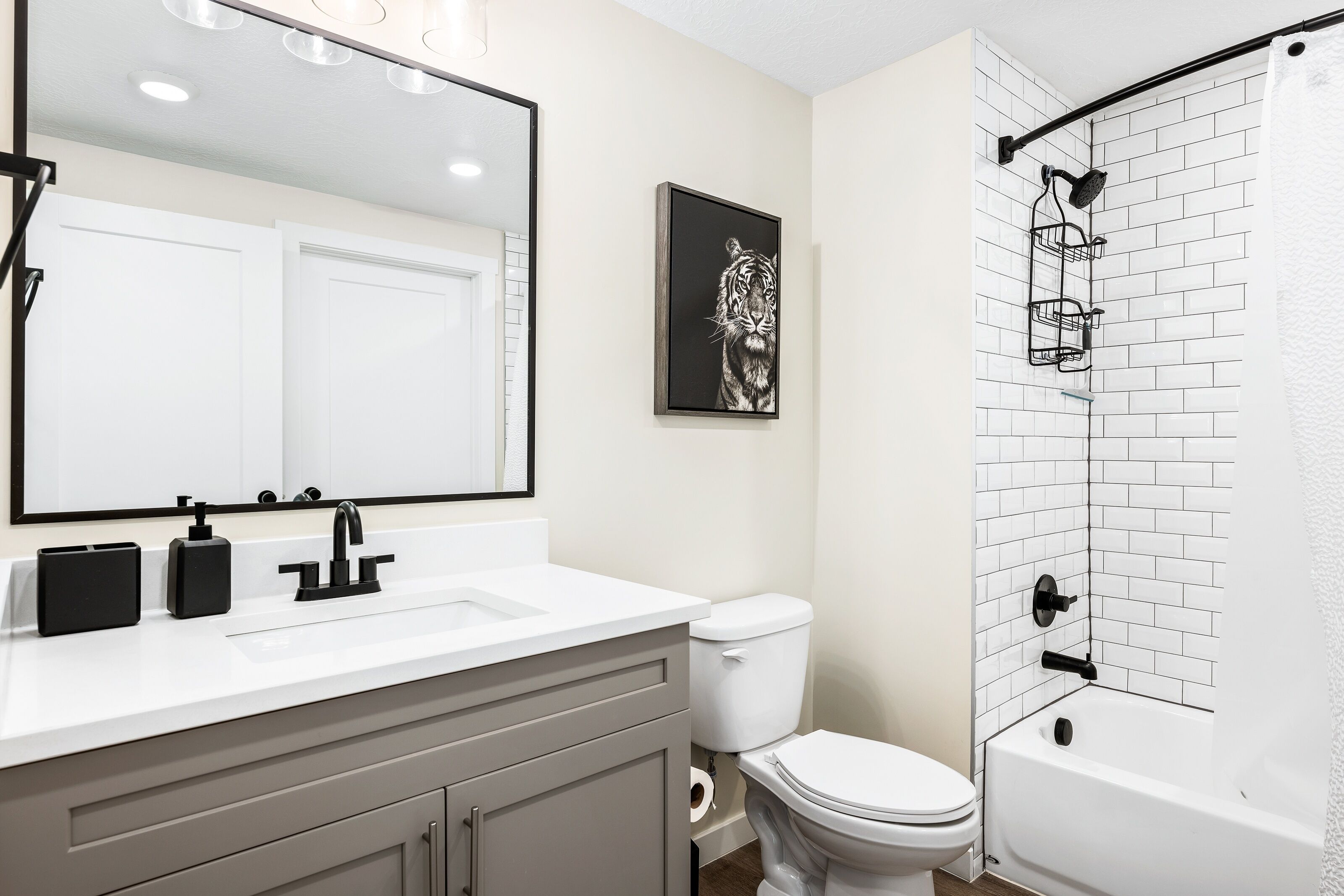 Un bagno con un lavandino bianco, un water, una vasca da bagno e una doccia con un portasciugamani nero.