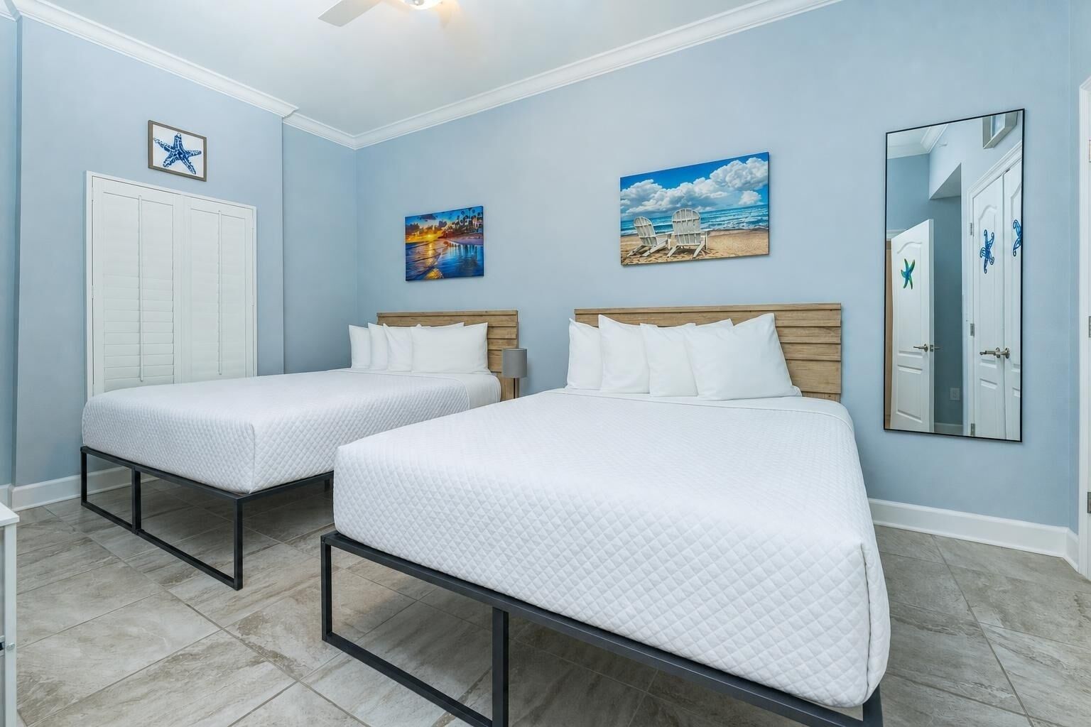 Ein Hotelzimmer mit zwei Betten, einem hölzernen Kopfteil, einem Deckenventilator und Bildern an den Wänden.