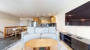 A modern living room with a sofa, wooden coffee table, and a flat-screen TV mounted on the wall. - Lakeview Villas #09 3 Bedroom Condo by RedAwning (Mammoth Lakes)