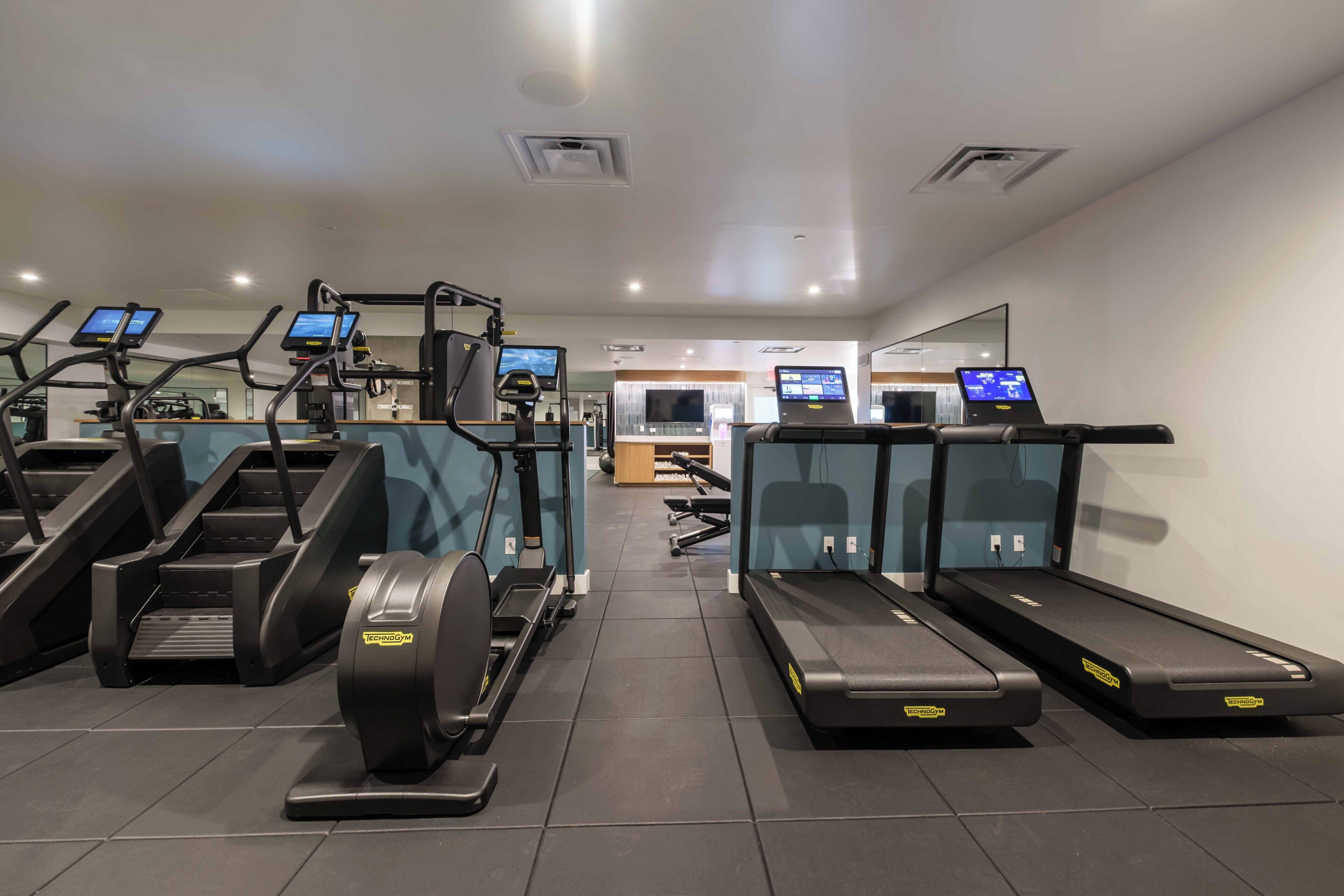 A gym with treadmills, elliptical machines, and exercise bikes.