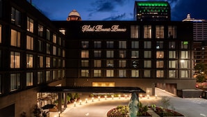 Un hotel con un cartel llamativo, un patio central con una escultura y una estructura en forma de cúpula al fondo.
