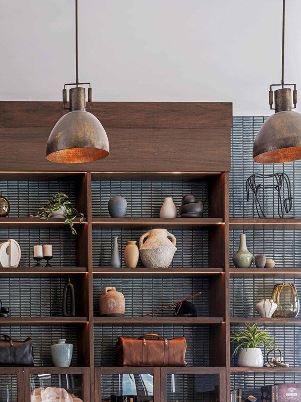 Una habitación con estantes de madera que exhiben varios objetos decorativos y dos lámparas colgantes de estilo industrial.